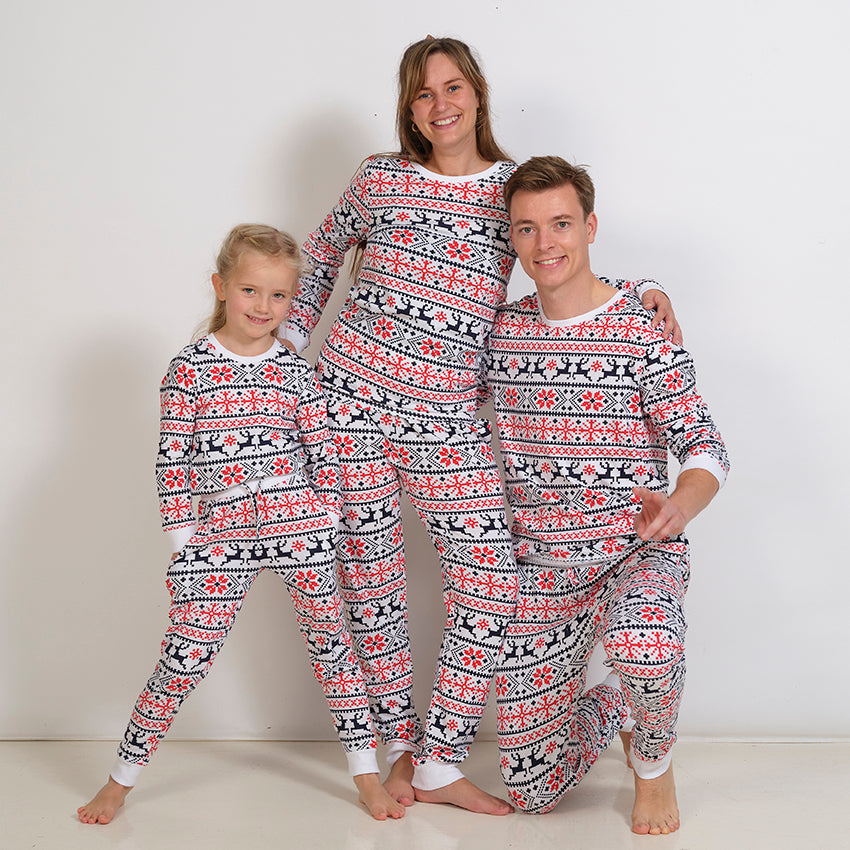 En dame, en mand og et barn iført hvide julepyjamas med julemønster.